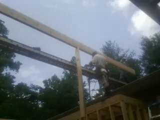 Carpenter setting a ridge beam over a new addition frame — Ice Dam Removal by Roofing Brothers in Welches