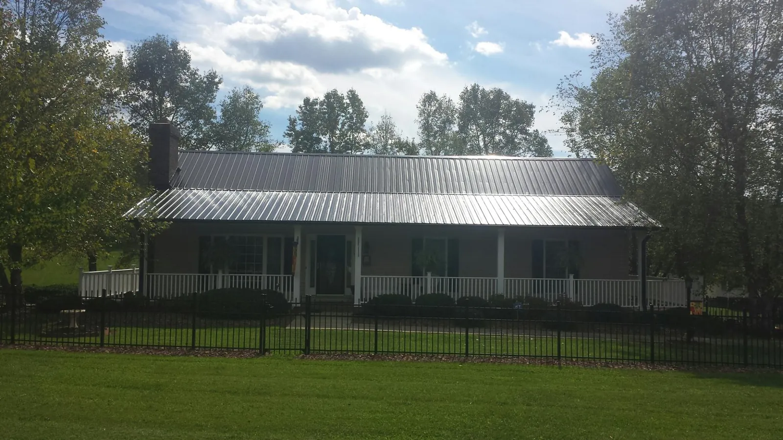 Gray metal roof on a brick ranch with a full width front porch — Gutter Guard Installation work by our crew in Welches