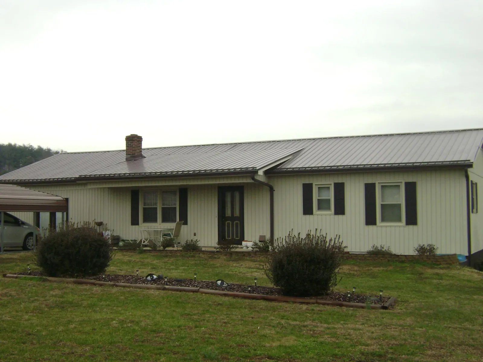 Brown metal roof on a cream sided ranch home with a brick chimney in Welches