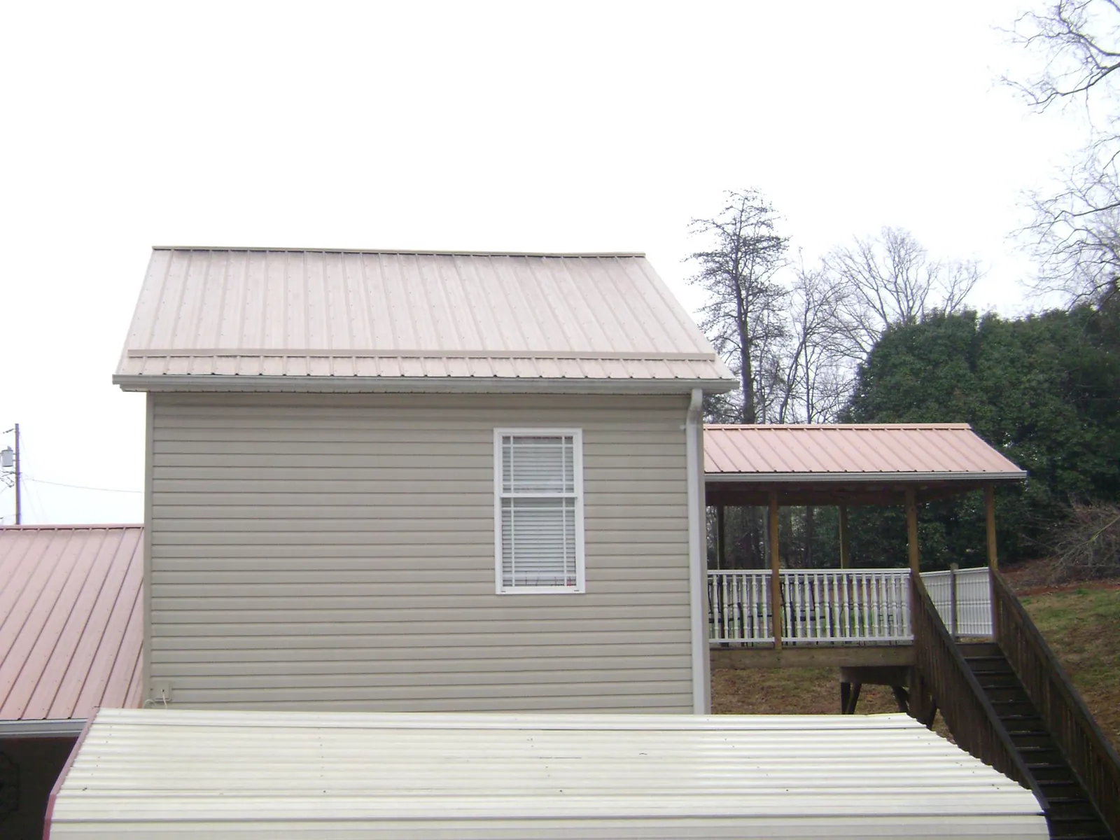 Tan metal roofs on a two story addition and attached porch, from a Roof Replacement job in Welches