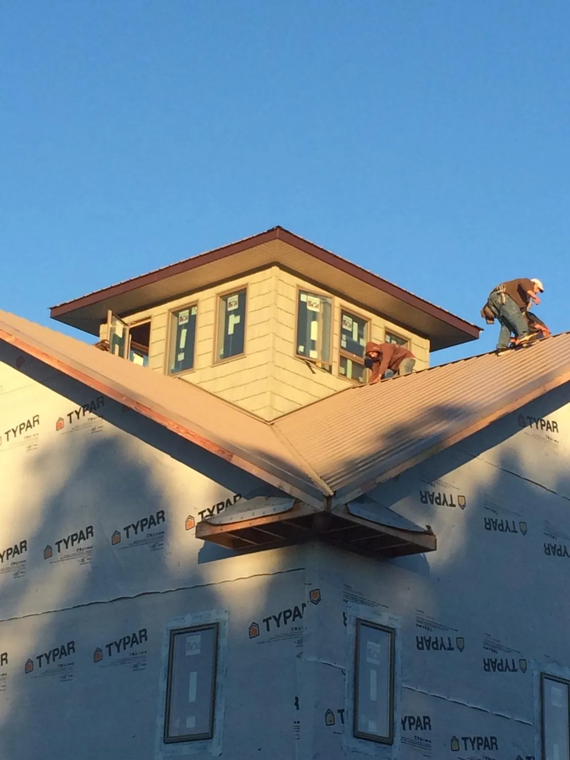 Roofers working around a rooftop cupola on a new metal roof at sunset — Roof Waterproofing in Welches by Roofing Brothers